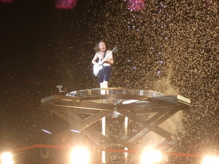 Angus Young tocando guitarra em palco com o AC/DC